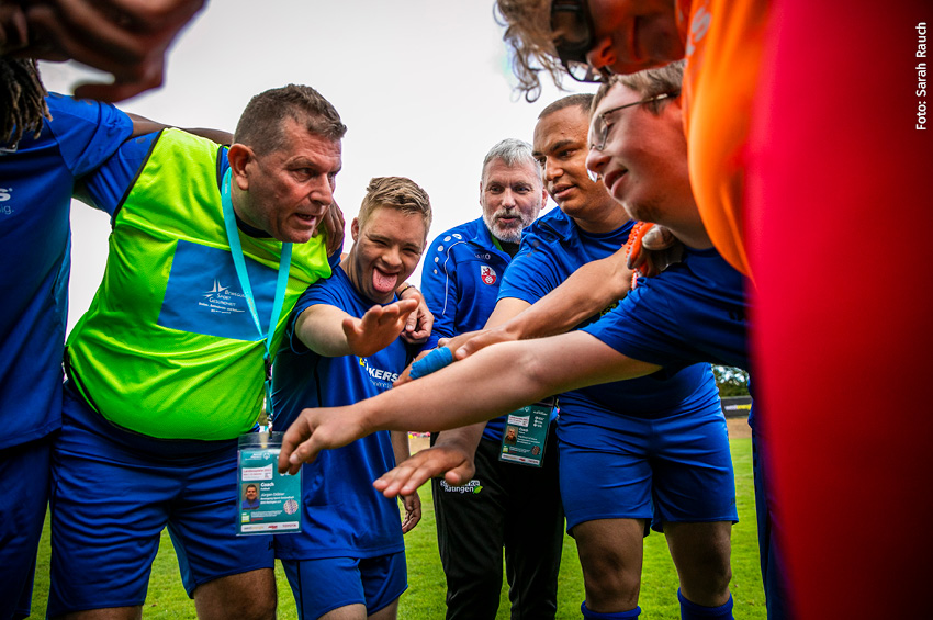 Eine Gruppe Sportler, die auf dem Spielfeld zu einer Besprechung zusammengekommen ist